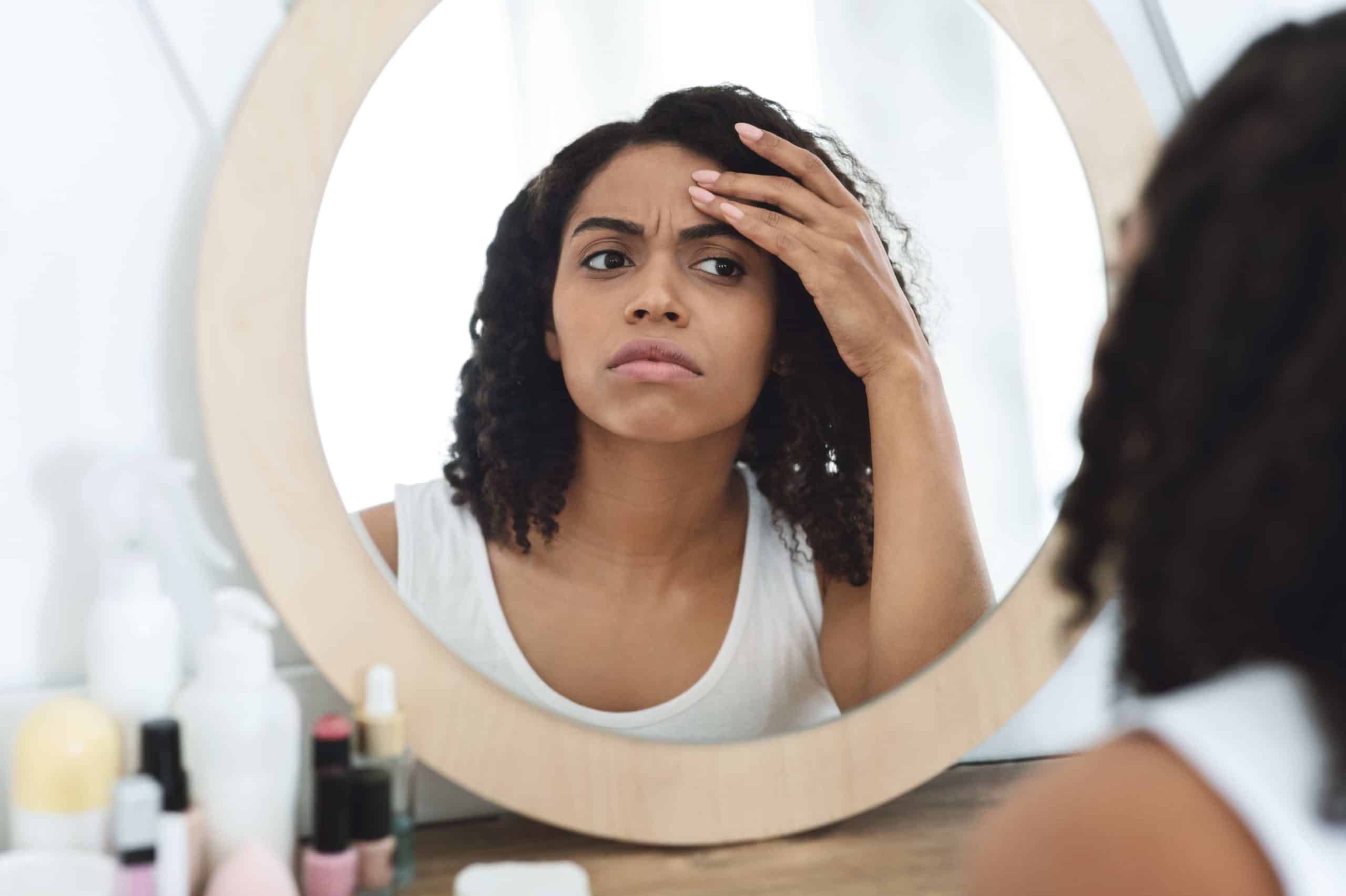 Woman Checking Wrinkles of Forehead on the Mirror | Skynn MD in Holly Springs, NC